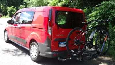 The red Renaissance Cyclery van with a customer's bicycle loaded on its hitch rack